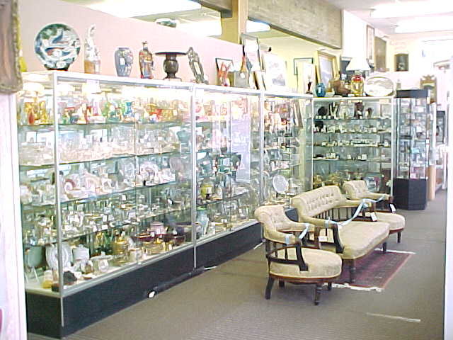Long glass cases holding jewelry and figurines, with antique parlor chairs