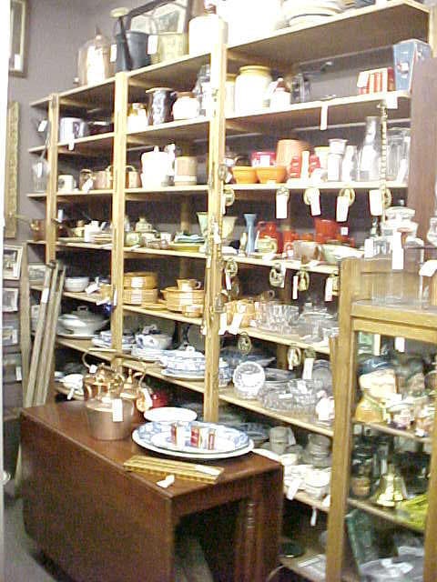 Shelves densely loaded with antique pottery, china, and dishware