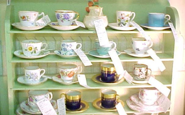 Antique teacups and saucers on a jade-green painted shelf