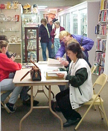 Collectors seated at community tables browsing reference books in the Collectors Bookstore
