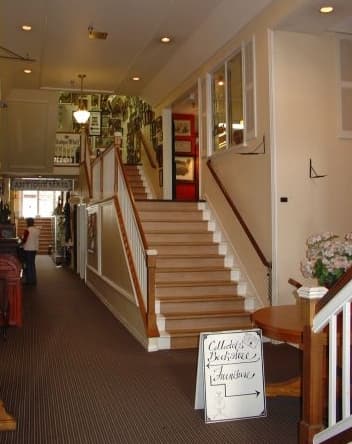 The wide wood staircase with white railings and a handwritten Collectors Bookstore sign